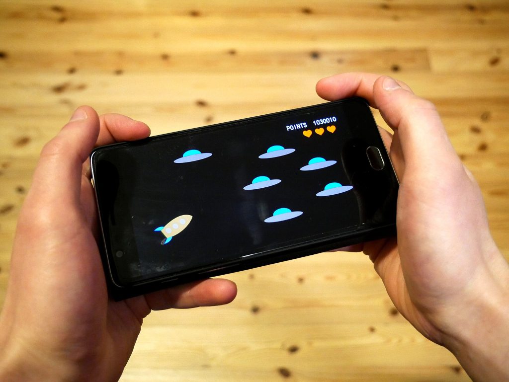 A person holding a smartphone playing a colourful mobile game