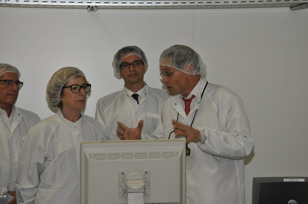 Engineer holding a silicon wafer in a bright cleanroom